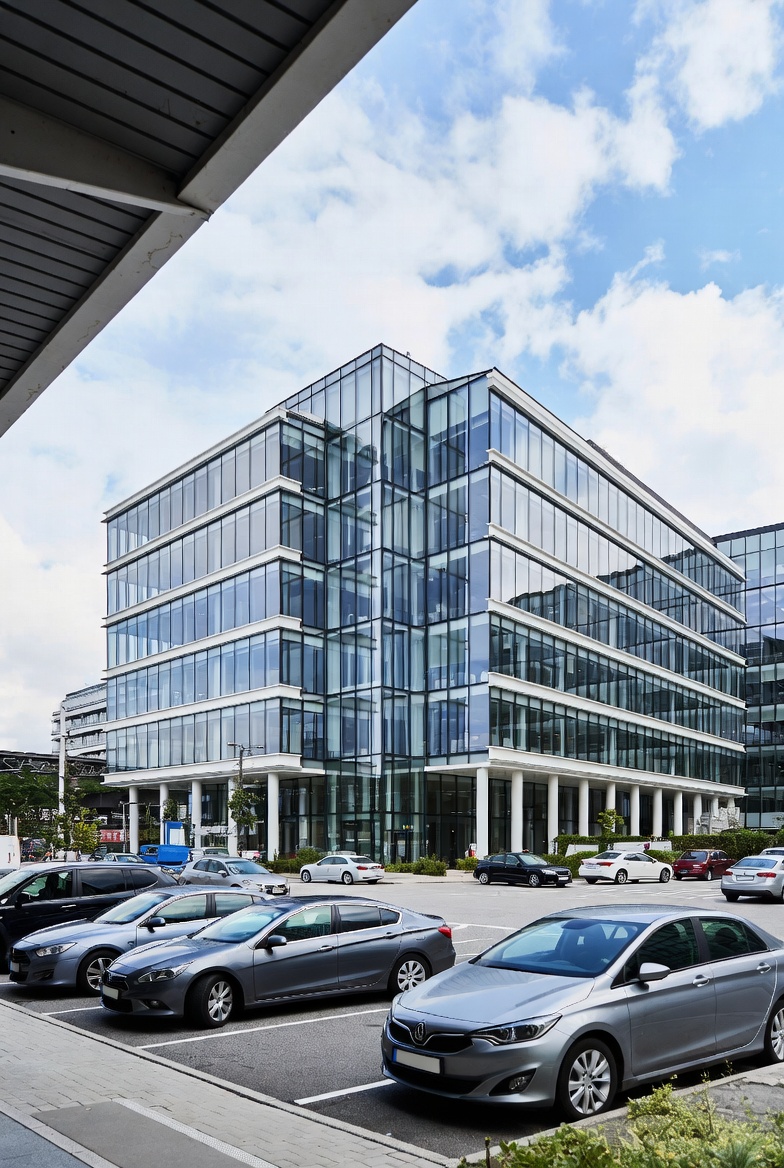 Moderne glasbygning til erhvervslokaler placeret tæt på et trafikknudepunkt med parkeringsplads foran